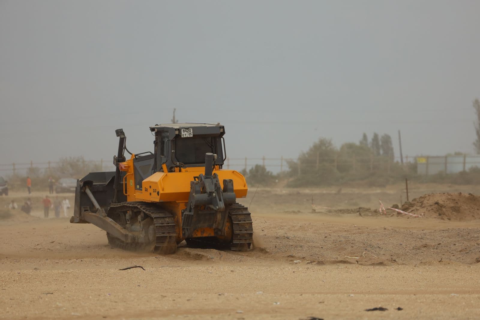 Tracked dozer pushing material on a dusty site