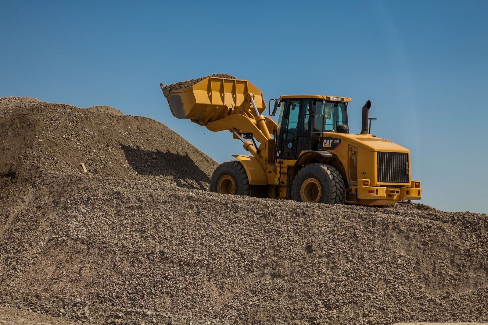 Yellow wheel loader moving aggregate on a stockpile