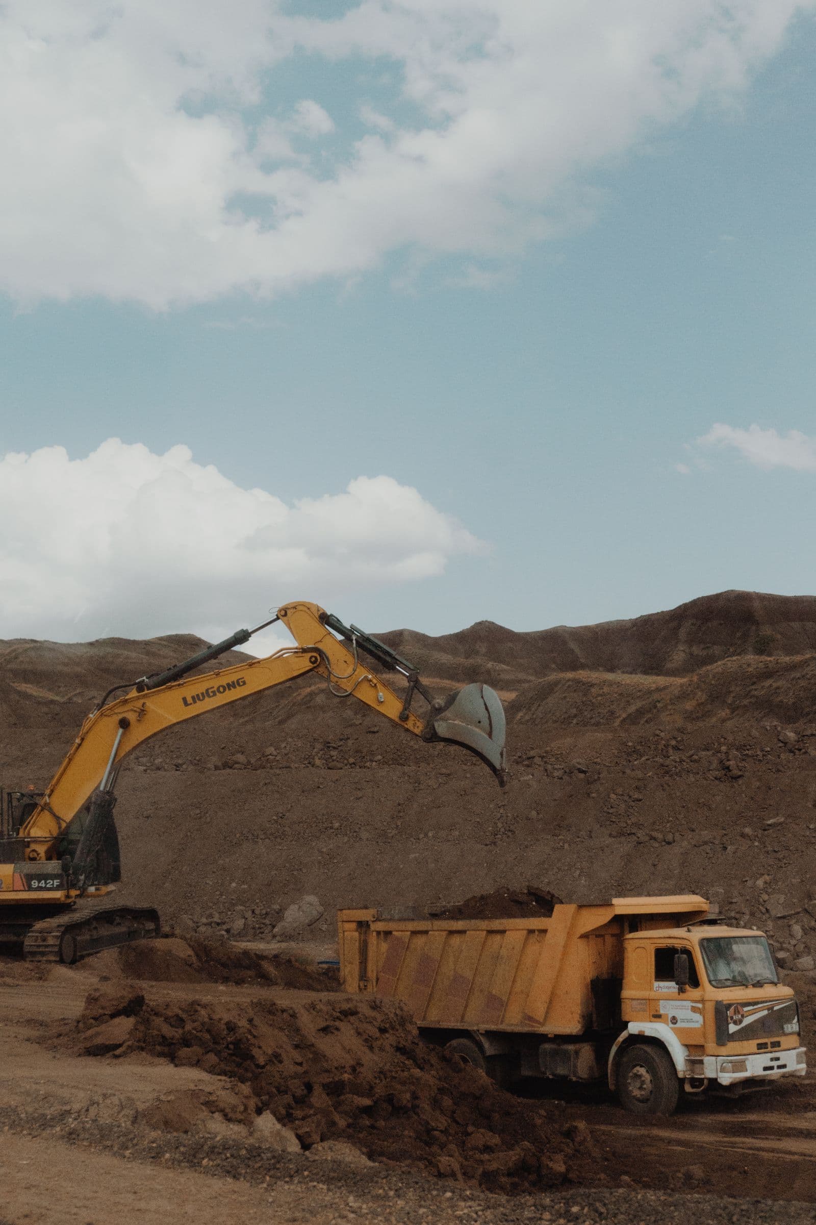 Excavator loading a dump truck in an open mining landscape