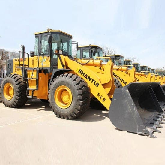 Yellow wheel loaders lined up in a yard